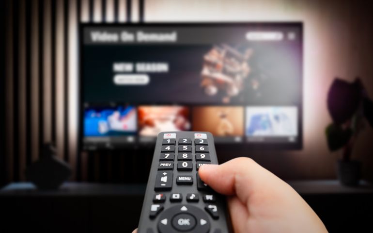 Man watching TV with remote control in hand.