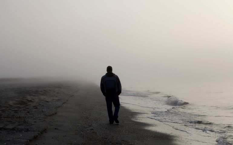 Man walking alone on a foggy beach
