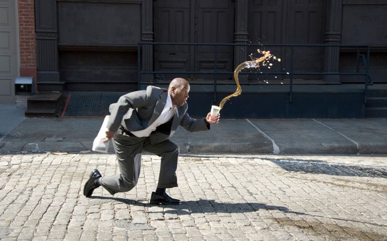 Businessman outdoors, spilling cup of coffee on pavement, side view