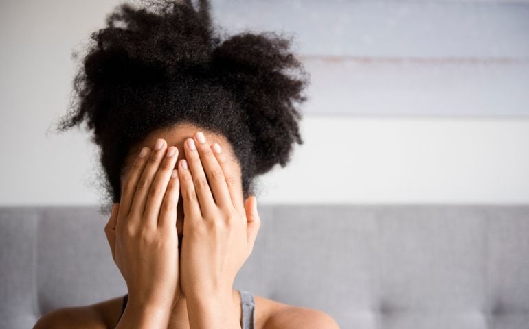 African American woman covering face with hands