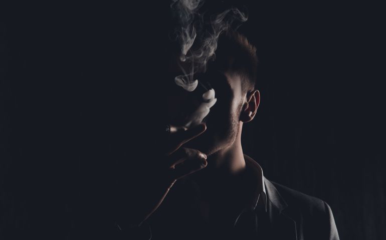 Mystery man with cigar and smoke isolated on black background
