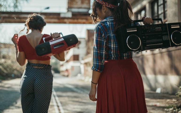 Young women listening to music from a boom box and having fun outdoors