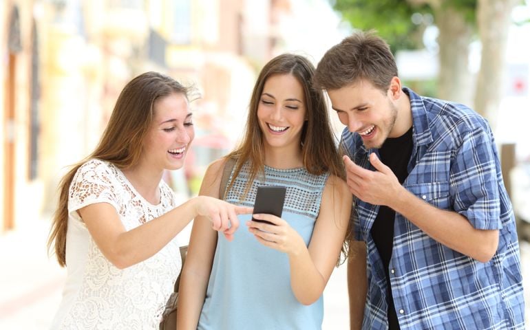 Friends watching smartphone content in the street
