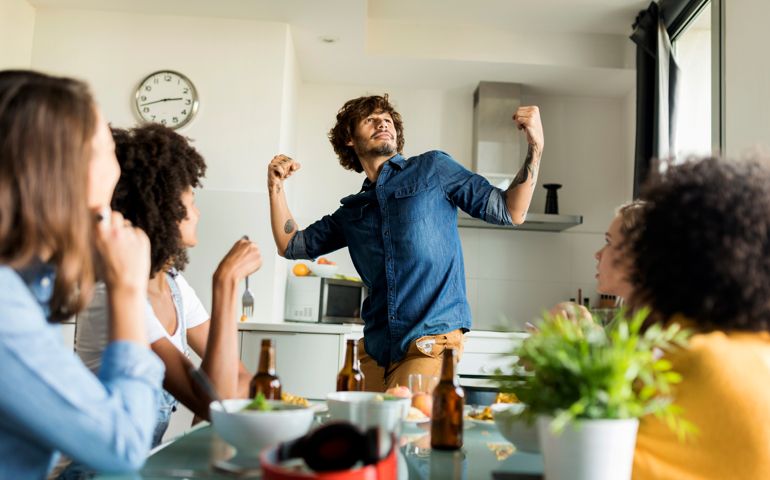 Woman sitting at dining table watching man posing