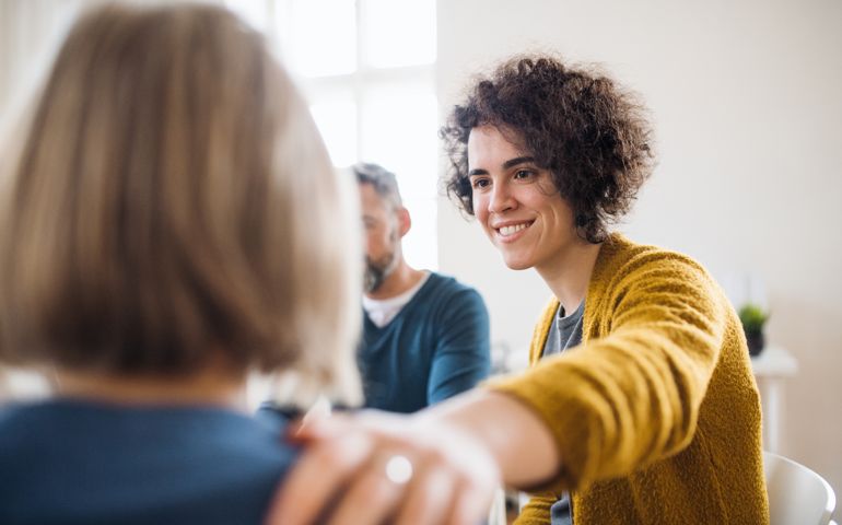 Men and women sitting in a circle during group therapy, supporting each other.