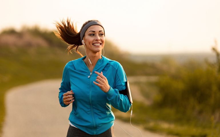 Happy female runner jogging in the morning in nature.