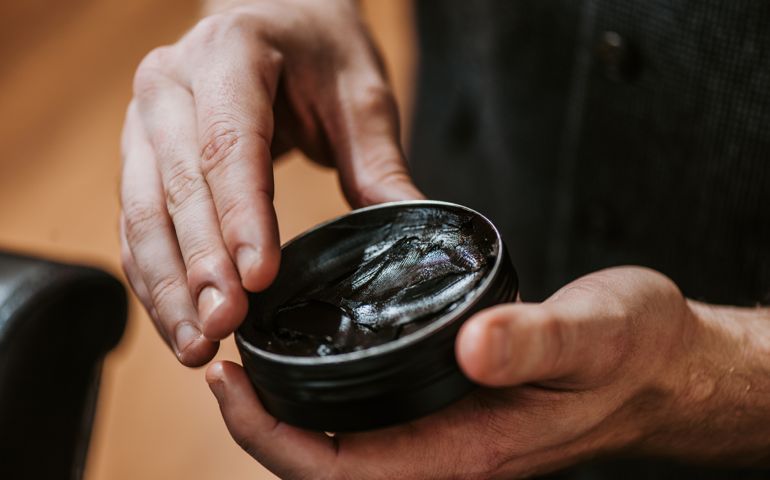 cropped view of man holding jar with black hair pomade