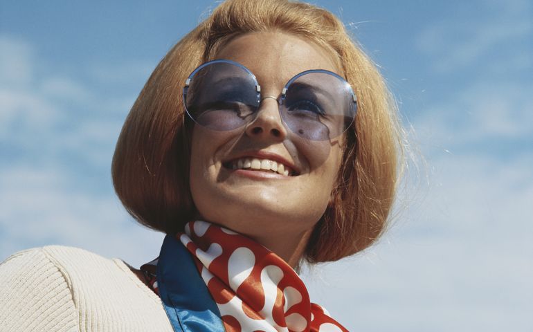 Young woman wearing sunglasses, smiling, close-up