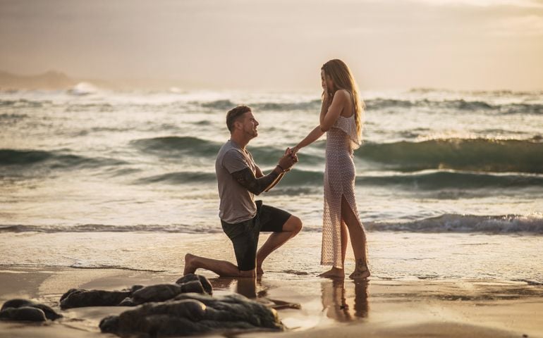 Young man proposing to his girlfriend at a beach