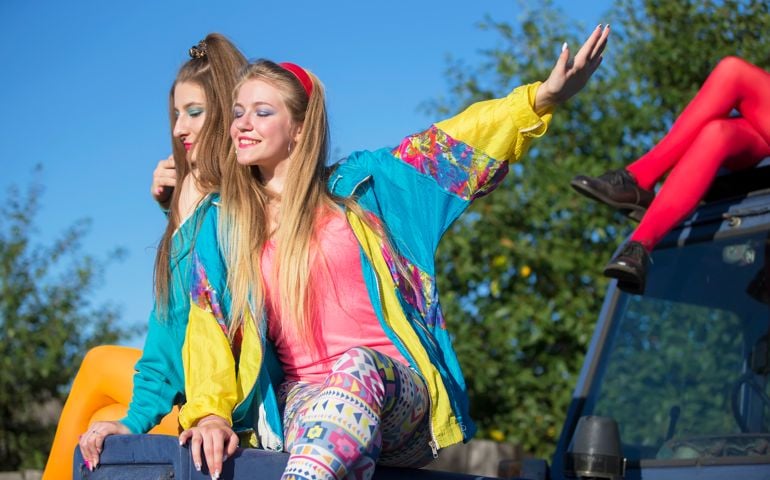 Beautiful country girls dressed in the style of the nineties sit on a tractor.