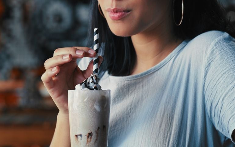 Shot of a woman enjoying a delicious milkshake at a diner