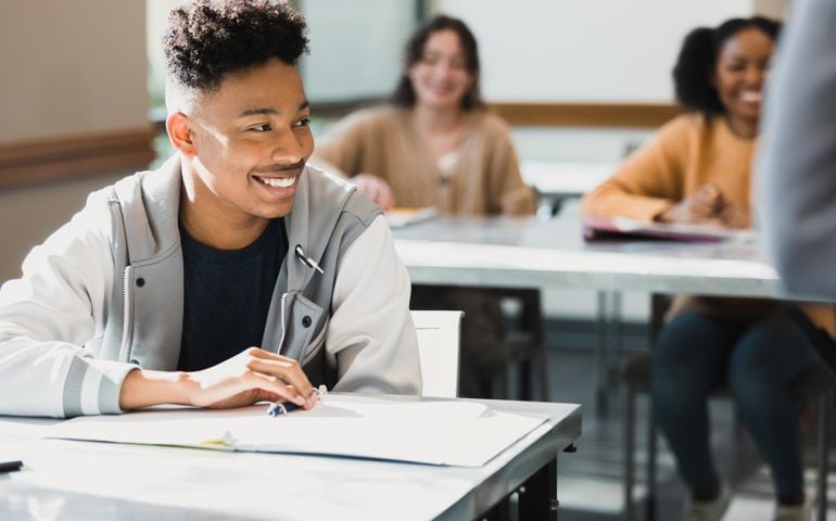 Confident male high school student smiles during class