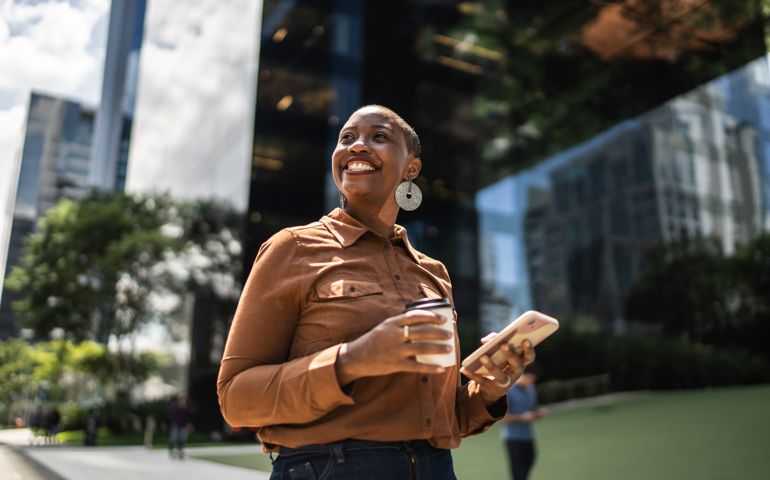 Business woman holding smartphone and looking away outdoors