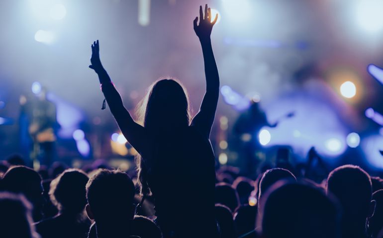 Silhouette of a woman with raised hands on a concert