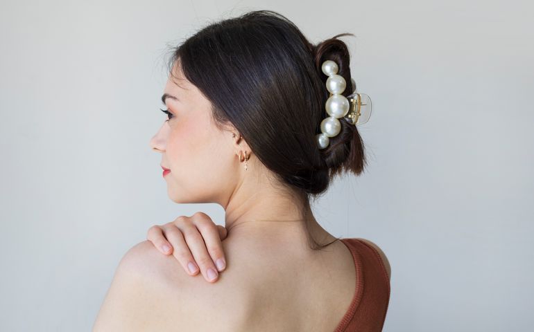 Young woman with beautiful hair clips on grey background