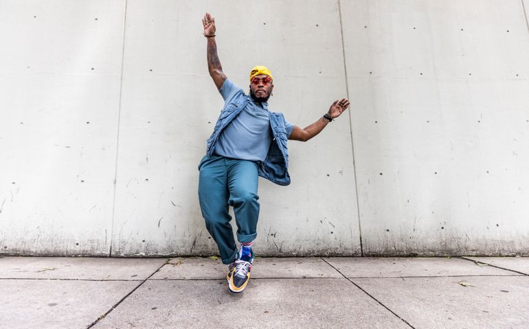 Fashionable male professional dancer on urban sidewalk, full length
