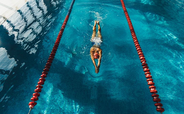 View from above of woman swimming by track in the pool. Sports concept, unrecognizable person.