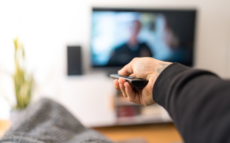 man on sofa changing TV channel
