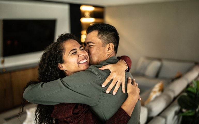 Mid adult couple embracing in the living room at home