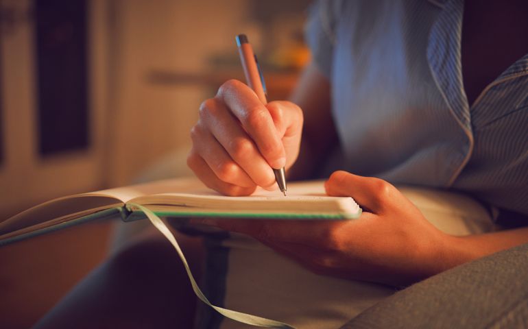 Creative writing at home by female hands enjoying a calm, peaceful day off indoors. Woman making notes in a journal, expressing her feelings and thoughts while making a note of a personal experience