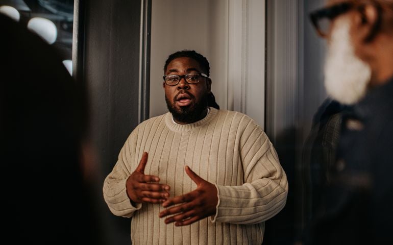 A man is animated as he uses hand gestures and talks to onlookers
