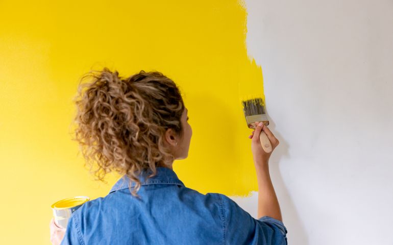 Woman at home painting a wall yellow