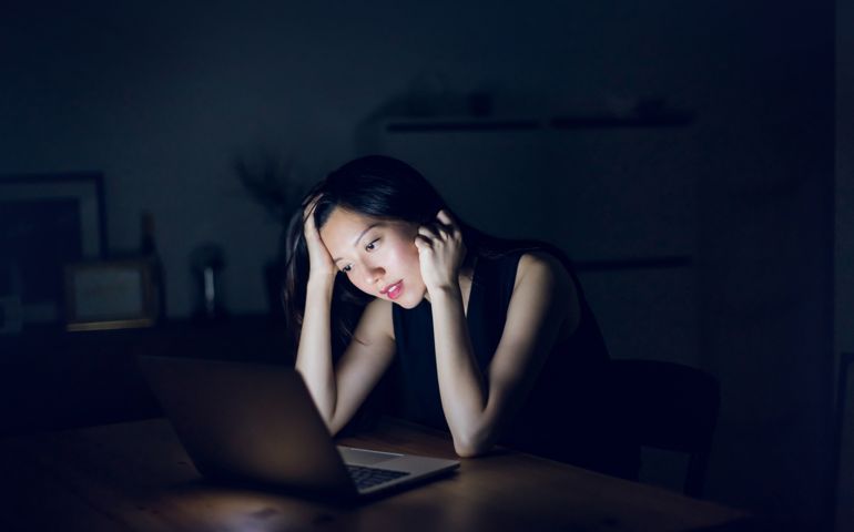 Stressed and frustrated businesswoman working on laptop till late at work
