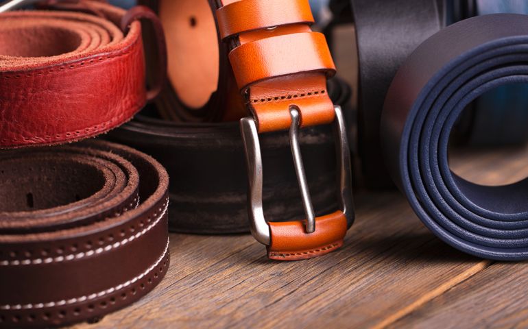 Collection of leather belts on a wooden table