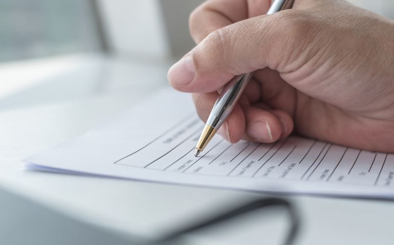 Applicant filling in company application form document applying for job, or registering claim for health insurance