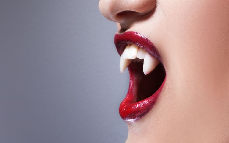 Sexy vampire. Women's lips with red lipstick. Screaming mouth with vampire fangs
