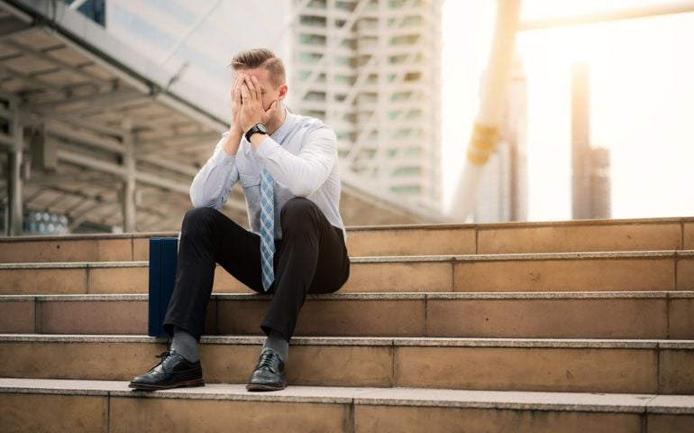 Young business man crying abandoned lost in depression sitting on ground street concrete stairs suffering emotional pain, sadness, looking sick in grunge lighting