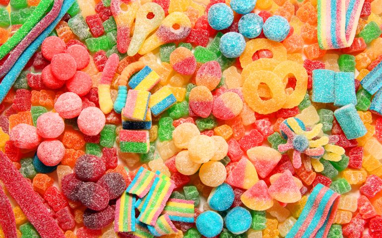 Assorted variety of sour candies includes extreme sour soft fruit chews, keys, tart candy belts and straws. Flat lay, sugar background concept for kids birthday party.