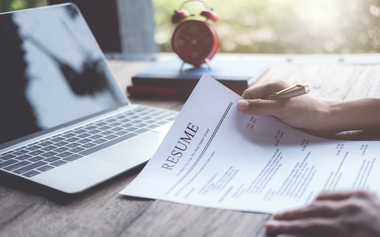Business man review his resume application on desk, laptop computer, job seeker