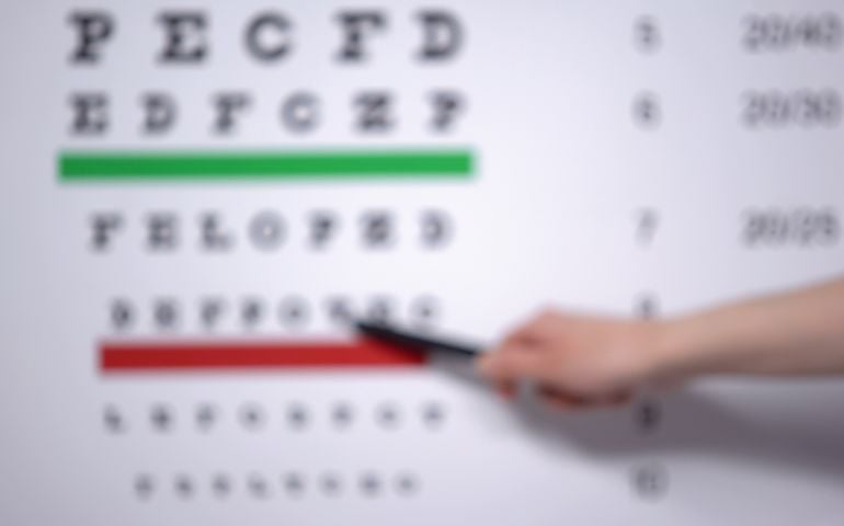 Ophthalmologist hand showing letter on eye chart to patient with vision problems