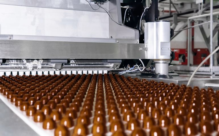 chocolate toppings on the conveyor of a confectionery factory close-up