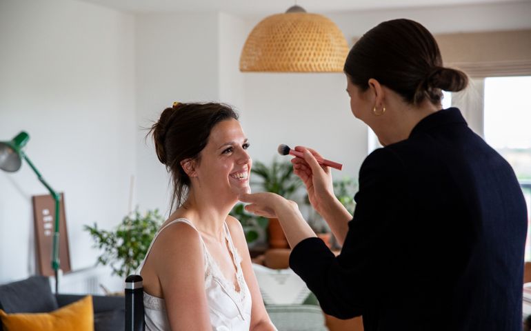 A professional make up artist at work, creating a look for a young woman.