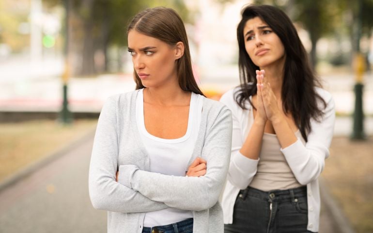 Girl Begging Offended Female Friend To Remain Friends Standing Outdoors