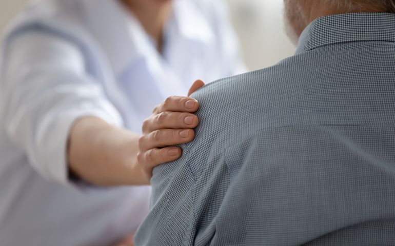Close up caring doctor touching mature patient shoulder