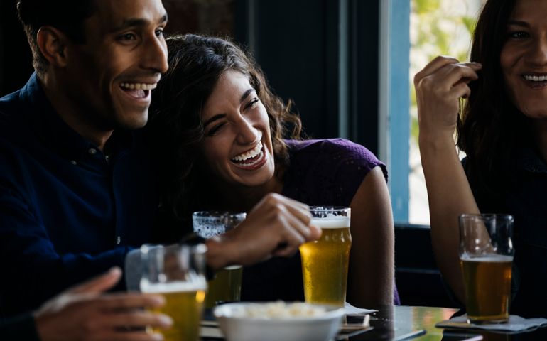 Friends laughing over drinks in bar