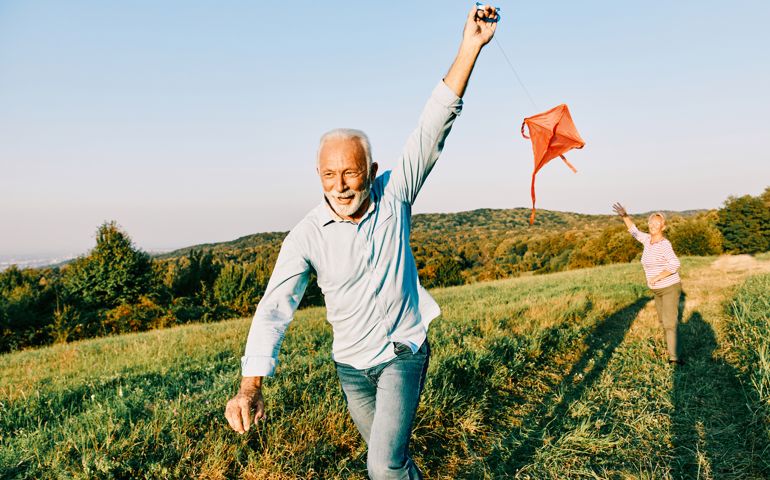 woman man outdoor senior couple happy lifestyle retirement together smiling love kite run nature mature