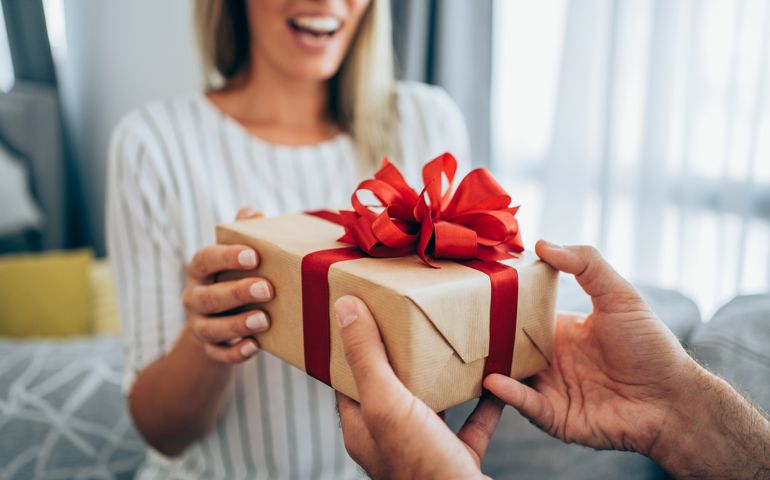 Cheerful young woman receiving a gift from her boyfriend.