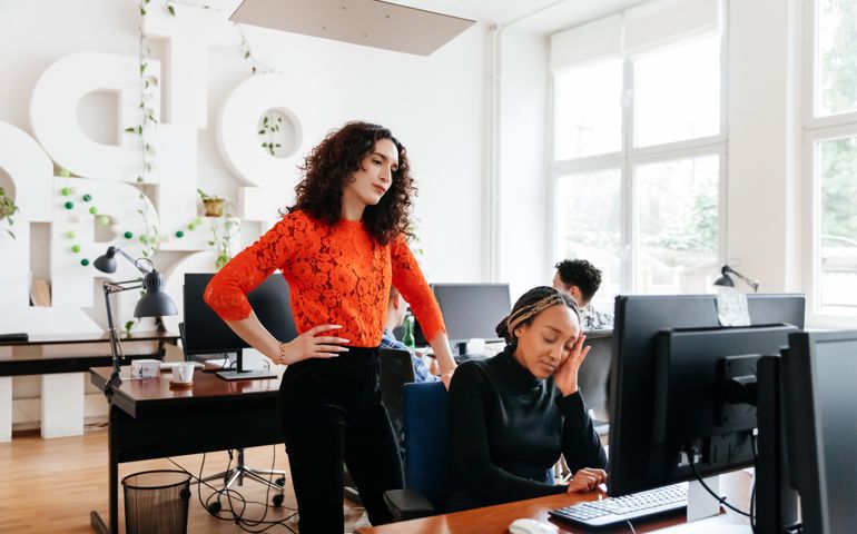 Business Manager Overlooking Colleague Working