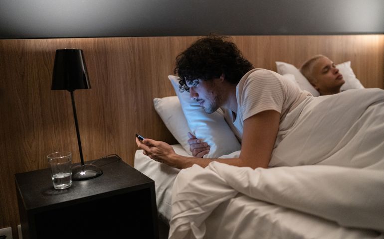 Young man checking smartphone at bed