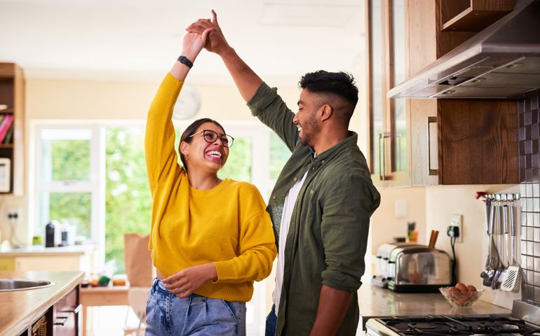 Shot of a young couple dancing together in their kitchen