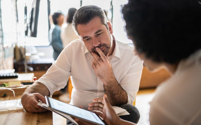 Mature man looking at a digital tablet that a colleague is showing at work