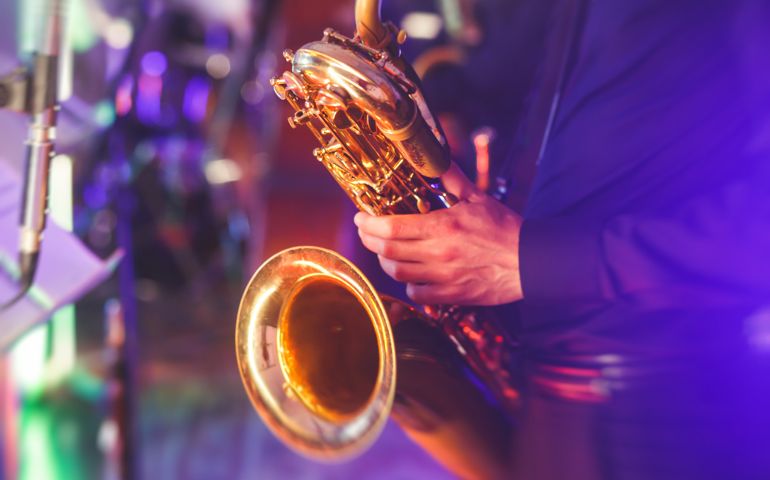 Concert view of a saxophone player with vocalist and musical jazz band in the background