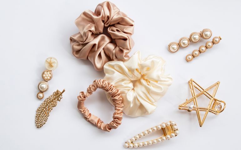 Collection of trendy silk elastic band scrunchies and pearl hair clips on white background. Diy accessories and hairstyles concept, luxury color