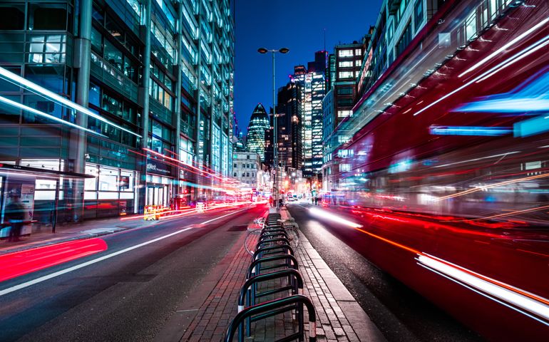 London red buses zooming through City skyscrapers night street