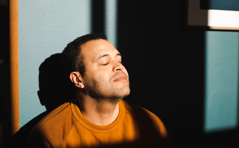 Man with eyes closed enjoying sunlight at home