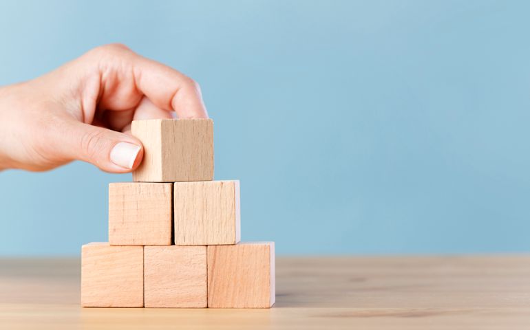 Woman hand flips blank wooden cube on top pyramid, place your own creative success symbols